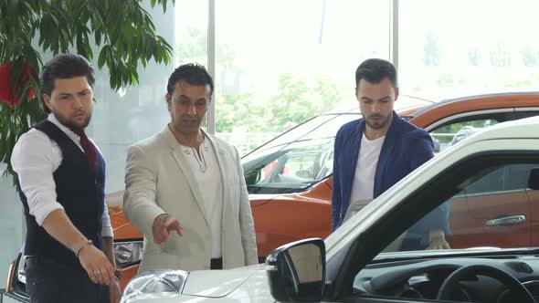 Three Male Friends Examining Car for Sale at the Dealership