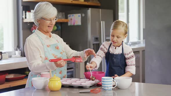 Happy grandmother and granddaughter filling cup cakes 4k