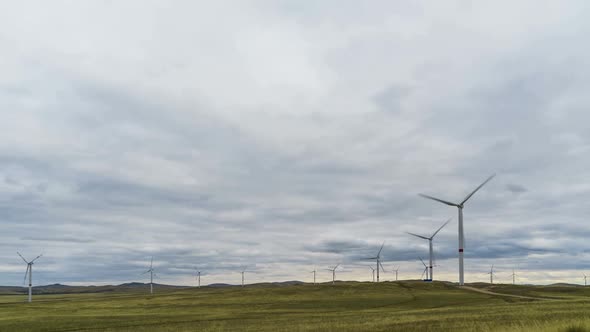 Blades of a Large Wind Turbine in a Field Against a Background of Cloudy Blue Sky on the Horizon