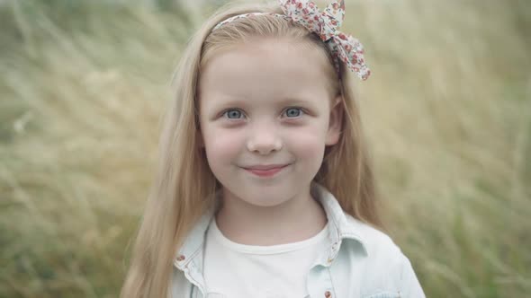 Closeup Portrait of Confident Beautiful Little Caucasian Blond Girl with Grey Eyes Looking at Camera