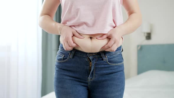 CLoseup of Young Woman in Jeans Holding Fat Fold on Her Belly