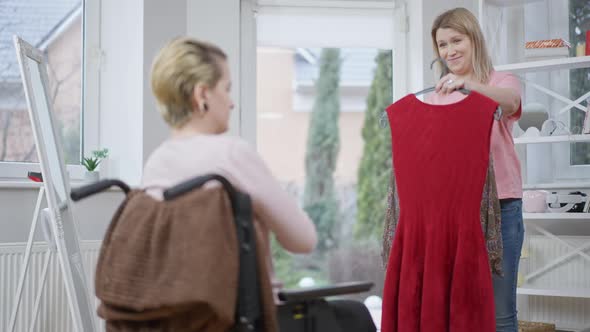 Portrait of Caring Woman Helping Handicapped Friend with Choice of Dress