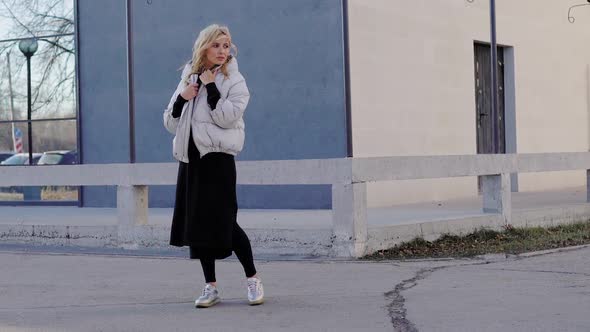 Outdoor Shot of a Blonde Model Posing in a Trendy Grey Coat By the Building in Autumn