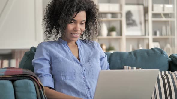 African Woman Celebrating Success on Laptop Sitting on Couch