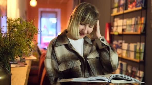 Portrait of Clever Student with Open Book Reading It in College Library