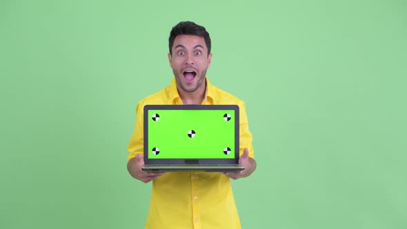 Happy Young Hispanic Businessman Talking While Showing Laptop