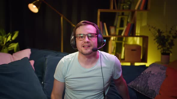 Young Man Gamer Wearing Headphones with Microphone Playing Video Game on Tv Gesturing
