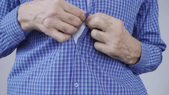 An Elderly Man Struggles to Button His Clothes