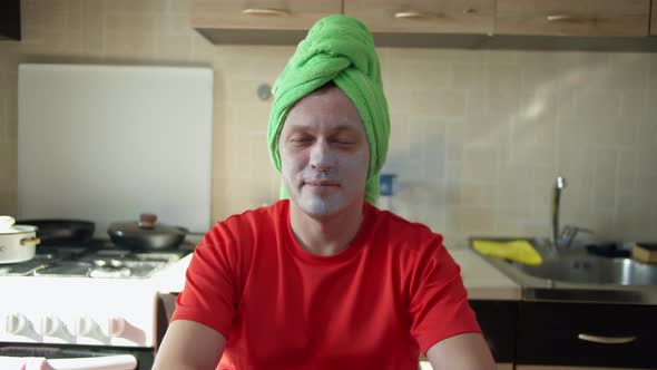 Pretty Man Sitting with a Cosmetic Mask on His Face and a Towel on His Head