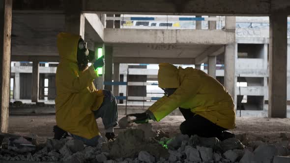 Two Mad Scientists in Yellow Overalls and Gas Masks Find Green Tube with Radioactive Substance in