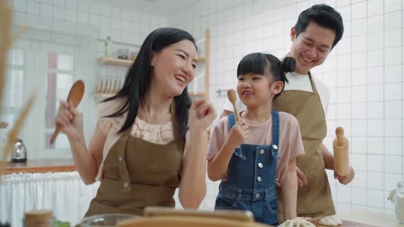 Asian happy family stay at home in kitchen spend time together dancing and baking bakery and foods.