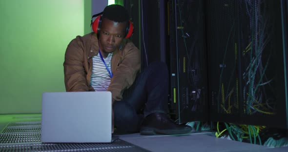 African american male computer technician using laptop working in business server room