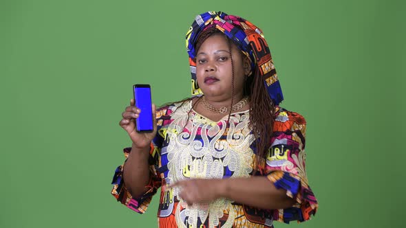 Overweight Beautiful African Woman Wearing Traditional Clothing Against Green Background