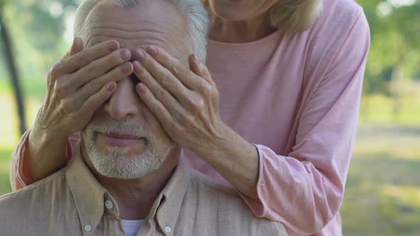 Old Woman Surprising Beloved Husband, Covering Mans Eyes From Behind, Happiness