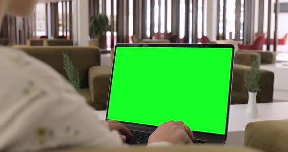 Digital nomad girl remote working on a laptop with green screen in the luxury hotel lounge.