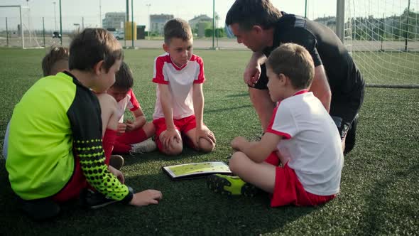 Coach Is Teaching Little Boys of Tactic of Football on Open Stadium