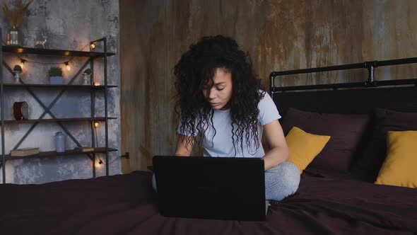Young Attractive AfricanAmerican Woman Using Laptop Computer in the Bed Dolly Shot