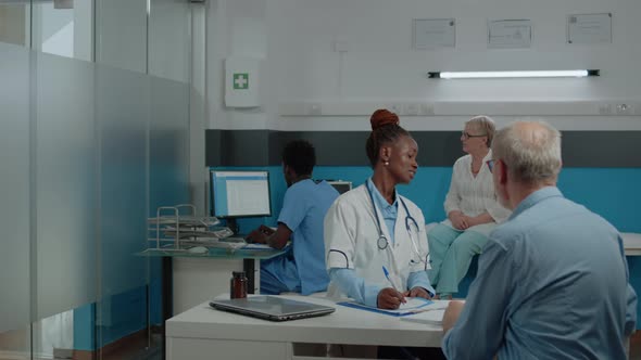 Young Medical Assistant Giving x Ray to Doctor Sitting at Desk alt