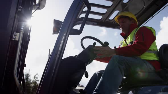 Warehouse worker driving forklift outside factory