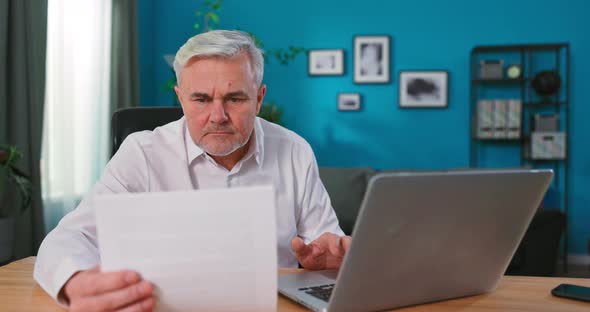 Old Senior Man Checking Home Finances and Bills He is Calculating Costs Using Computer and