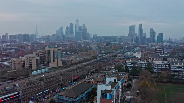 Falling drone shot from London city Skyline to Overground train line residential area