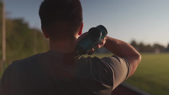 A Male Athlete Massages Muscles and Tendons with a Massage Percussion Device After a Workout at the