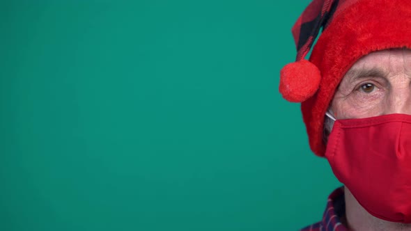 Portrait of Mature Man with Red Medical Face Mask and Santa Hat Looking at Camera