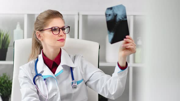 Focused Female Medical Worker in Glasses and Uniform Examining Patient Xray Medium Closeup