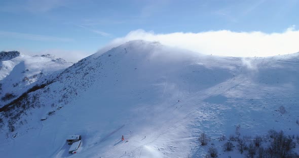 Forward Aerial Over Winter Snowy Mountain Top Ski Tracks Resort with Skier People Skiing