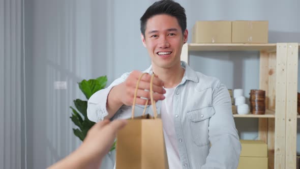 Portrait of Asian handsome business man handing package to customer in store.