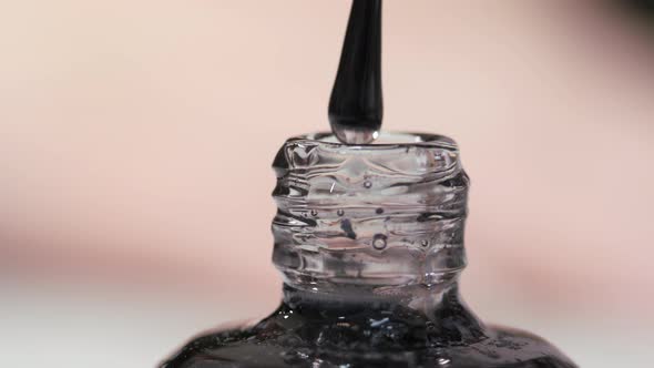 Manicure Brush is Lowered Into a Jar with a Transparent Varnish