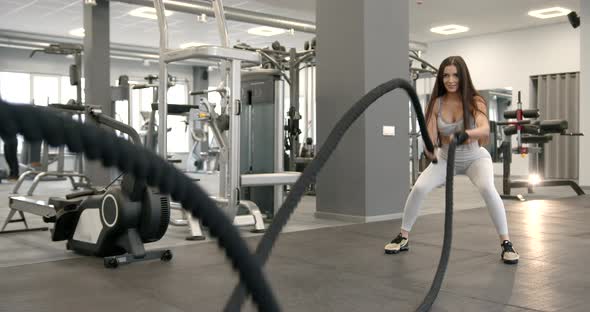 Athletic Girl Focused on Fitness Training with Ropes at Gym