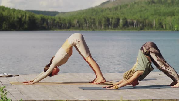 Two Fit Women Doing Yoga on Wooden Pier near the Lake