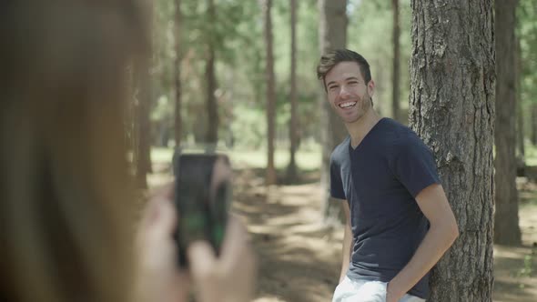 Woman photographing man using smartphone