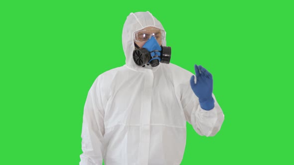 Medical Doctor in Hazamat Clothes Pointing on Imaginary Screen on a Green Screen, Chroma Key.