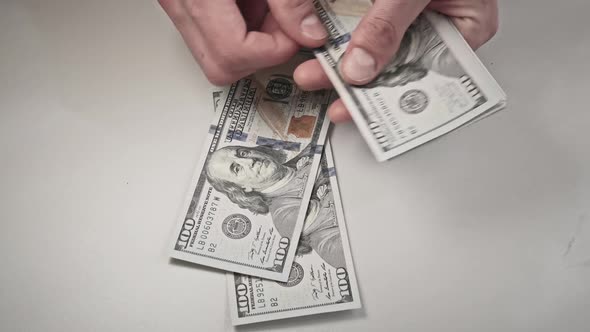 Male Hands Counting Old Hundred Dollar Banknotes on a White Table