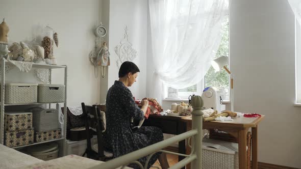 Woman sewing a doll in her studio