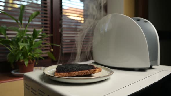 The man pulls out and places the burnt toast on a plate