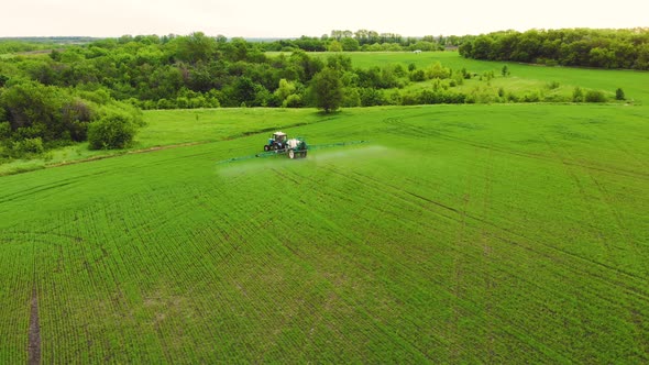 Aerial View of Farming Tractor Spraying on Field with Sprayer Herbicides and Pesticides at Sunset