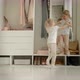 Twin Girls in Pajamas Play Against the Background of the Wardrobe - VideoHive Item for Sale