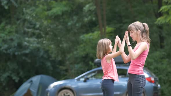 Young mother playing games together with her child daughter outdoors at camping site in summer.