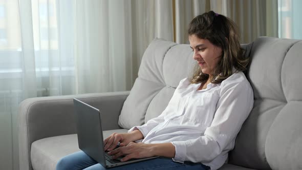 Disabled Woman Works on Computer Sitting on Sofa at Home