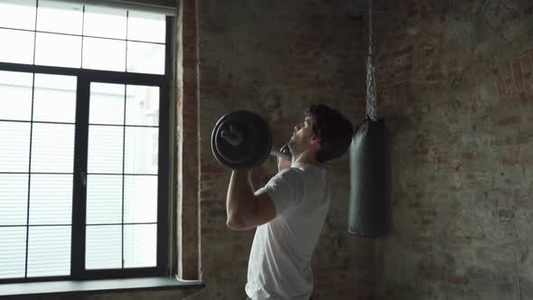 Muscular Fitness Man Lifting Barbell Above His Head in Modern Gym