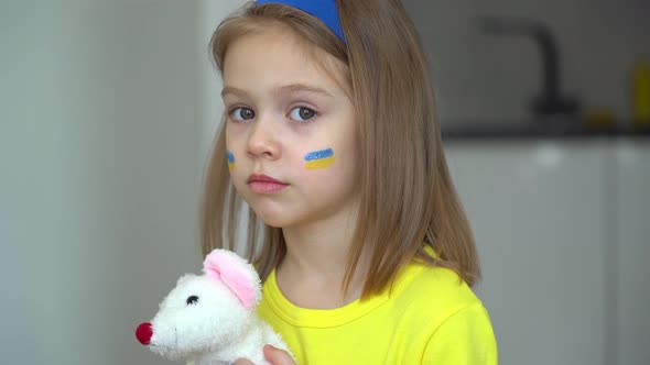 Girl with of Ukraine Flag on Face Looks at Camera
