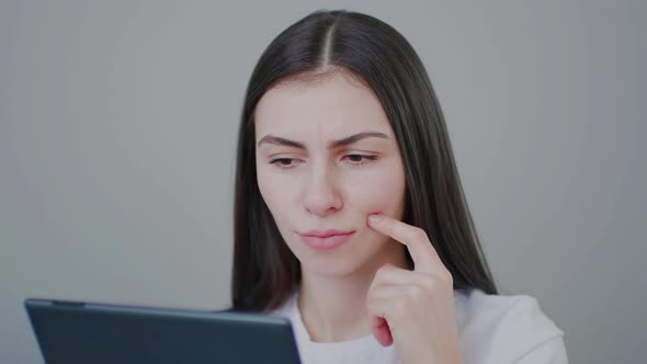 Millennial girl shaking head in dismay disbelief looking at tablet screen.