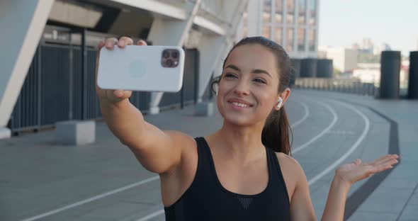 Young Fitness Woman Wearing Sportswear Having Video Call with Smartphone at Street While Sport