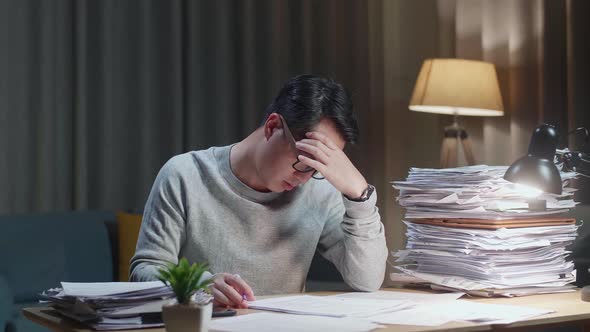 Tired Asian Man Shaking His Head While Working Hard With Documents At Home