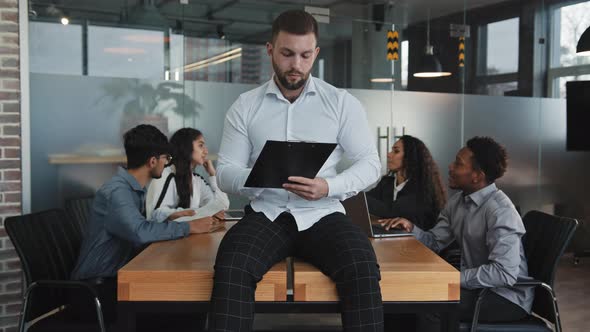 Serious Man Sit on Desk in Office Check Paperwork Pensive Businessman with Folder Write Business