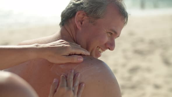 Closeup of Womans Hands Putting Sunblock Cream on Mans Back