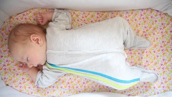 A Newborn Baby Calmly Sleeping in the Baby Cot